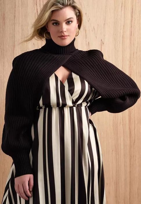 Model in a striped dress paired with a black turtleneck sweater scarf, posing indoors for a shopping feature