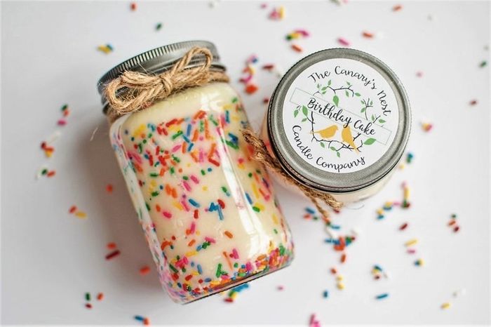 The candle — featuring a cream-colored design with funfetti sprinkles, housed in a glass jar