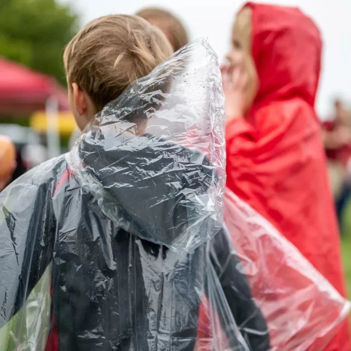 A child wearing a poncho at an outdoor event, prepared for rainy weather