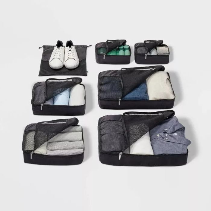 A variety of packing cubes neatly arranged with clothes and shoes, showcasing organized travel essentials