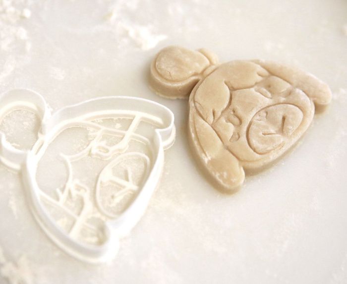 an Isabelle-shaped cookie cutter placed beside a sugar cookie shaped like Isabelle