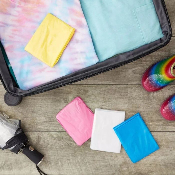 An open suitcase showcasing neatly arranged clothes, colorful shoes, and folded multicolor ponchos