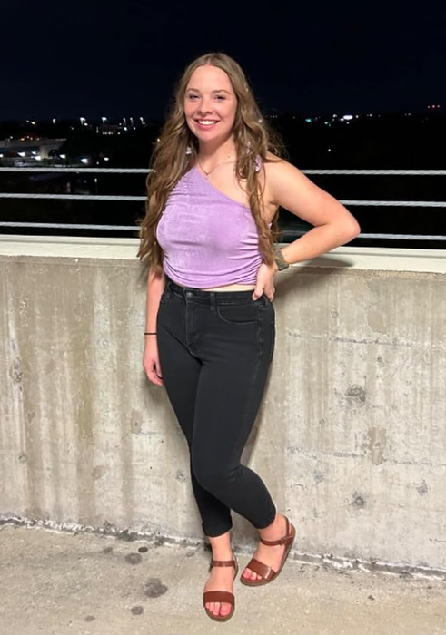 Reviewer posing outdoors in a purple asymmetrical top paired with black jeans