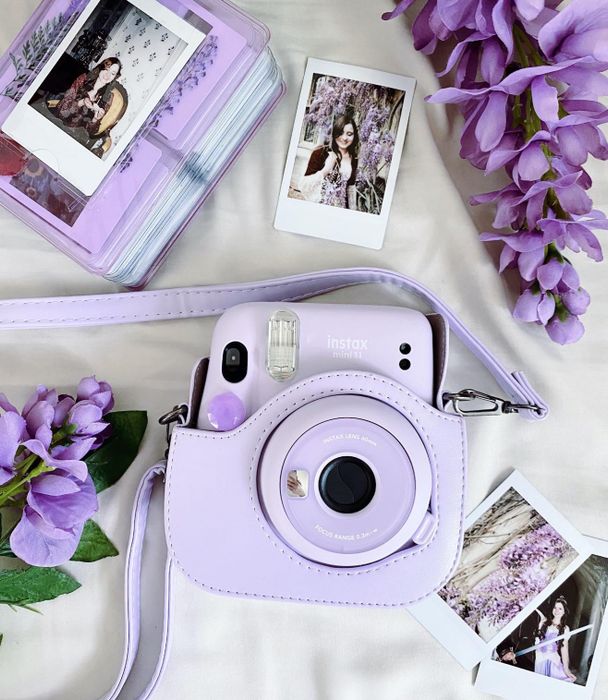 a reviewer’s photo of their lilac camera surrounded by scattered photos and flowers