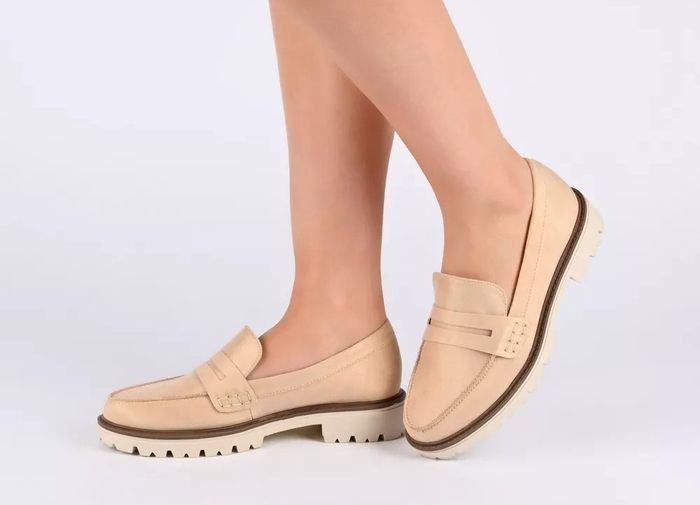 A person modeling beige loafers with a thick sole, highlighting both the style and comfort of the shoes.