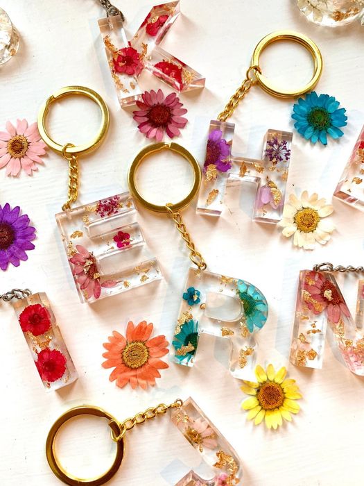 a collection of floral resin keychains featuring various letters