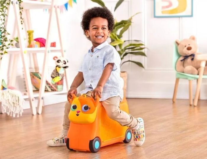 A child riding a toy scooter in a playroom, showcasing playful mobility