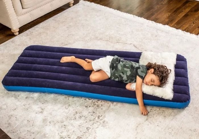 A child peacefully sleeping on a portable blue air mattress indoors