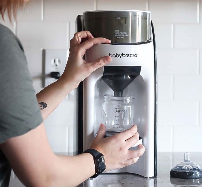 a model placing a bottle under the white and black formula machine