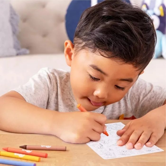 A child focused on coloring with crayons, showcasing creative play for shopping inspiration