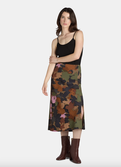 A model pairs a black tank top with a floral midi skirt and brown boots