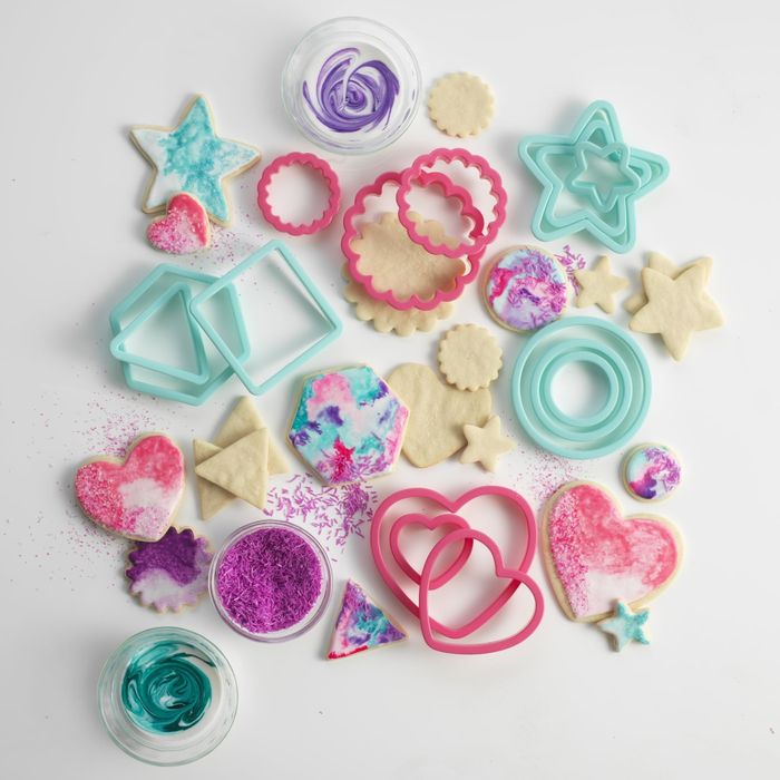 A collection of assorted cookie cutters alongside beautifully decorated cookies with vibrant icing and sprinkles, perfect for baking enthusiasts