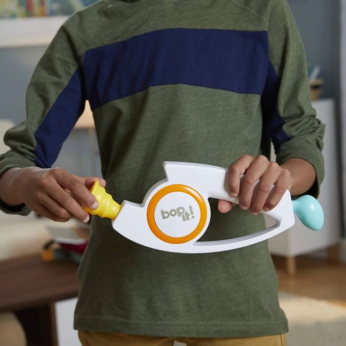 A person playing with a Bop It! electronic toy inside a home
