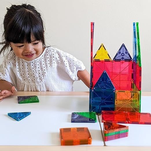A child engrossed in play, arranging colorful magnetic tiles on a table