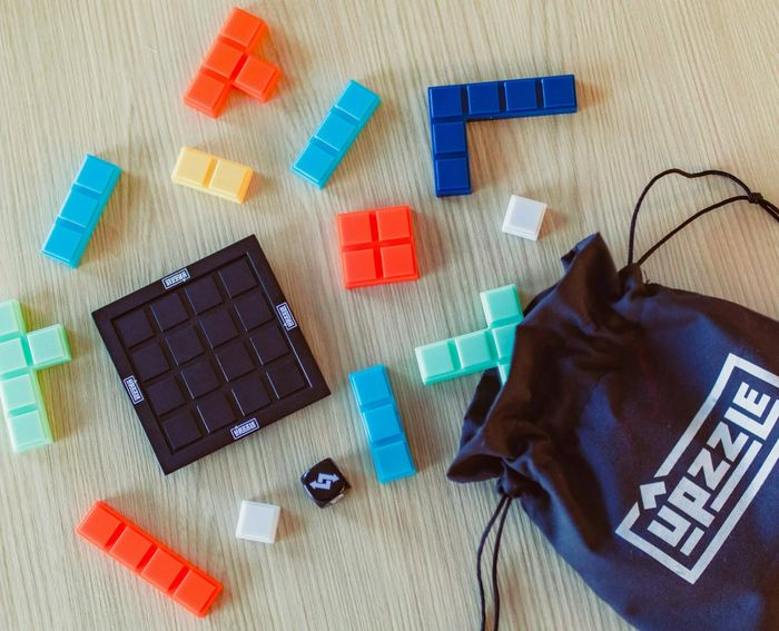 Includes puzzle game pieces, a board, and a branded drawstring bag. The caption states: 