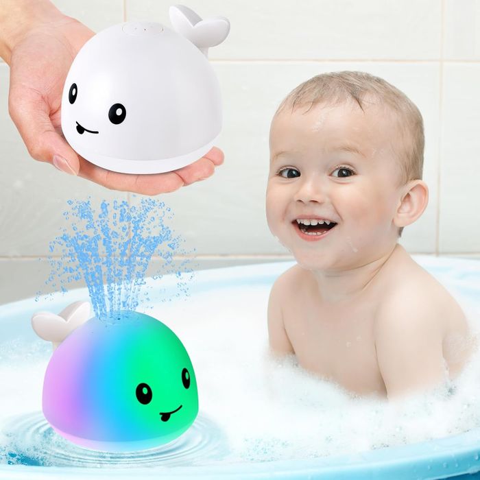 A cheerful baby in a bathtub, holding a smiling whale-shaped toy that sprays water, creating a joyful atmosphere