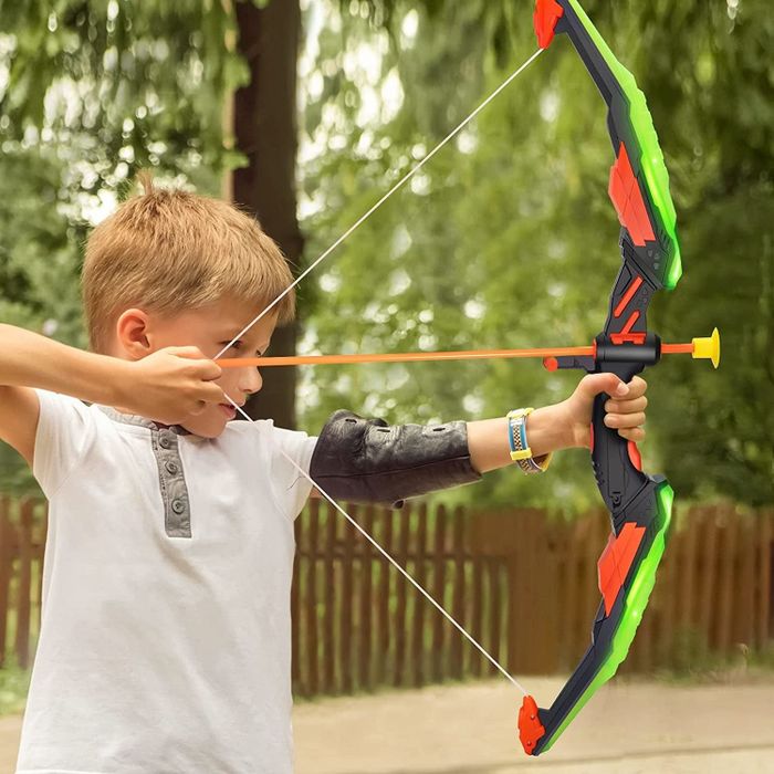 A young model holding a black and green plastic bow, poised to shoot a suction cup arrow
