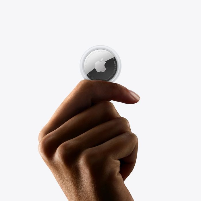 A person holding an Apple AirTag between their fingers, highlighting its sleek and compact design