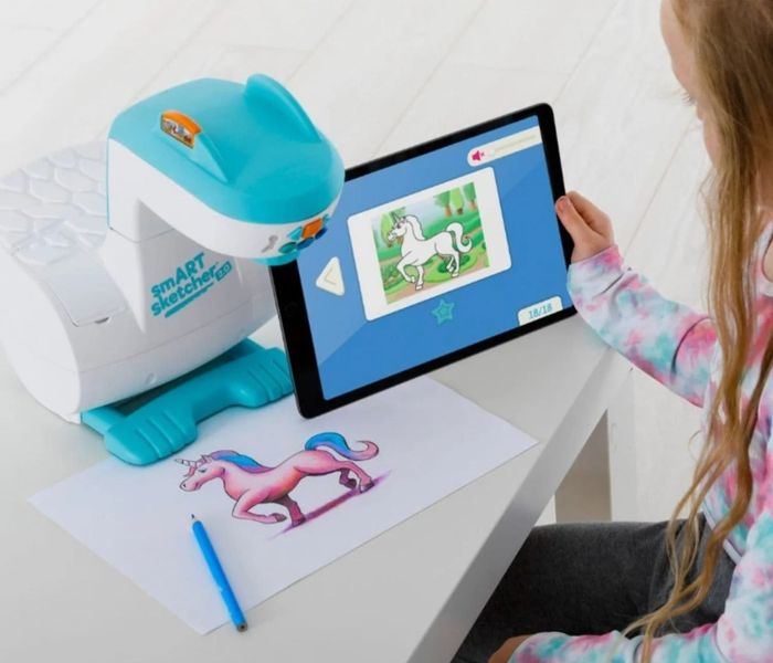 A child uses the smART sketcher projector alongside a tablet to sketch a unicorn. The image text reads: 