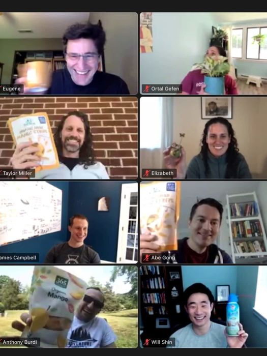A screenshot of a video call with participants each holding an assorted random object
