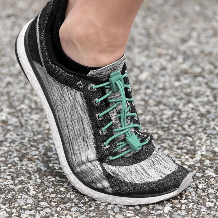 A close-up of a person’s foot wearing a sleek athletic shoe with innovative laces, perfect for running or everyday wear