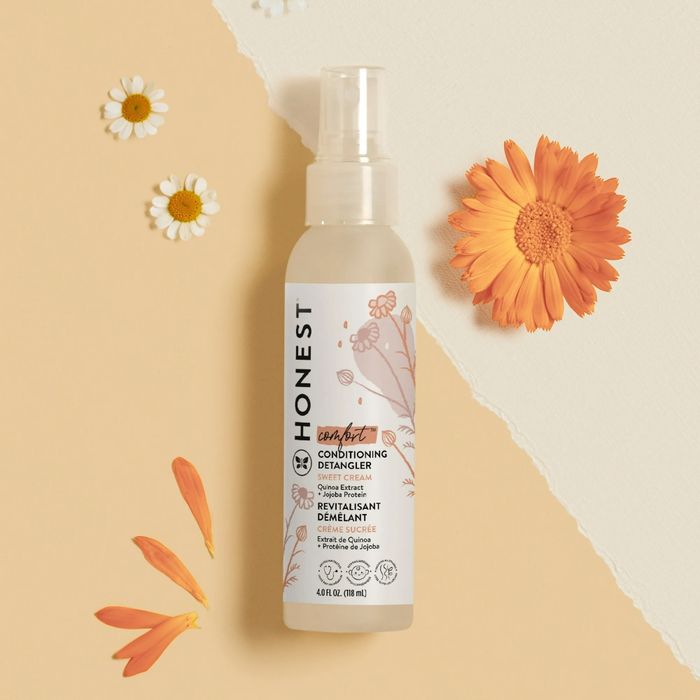 A bottle of Honest Conditioning Detangler displayed on a beige background with floral details, featured in a shopping article promoting hair care solutions