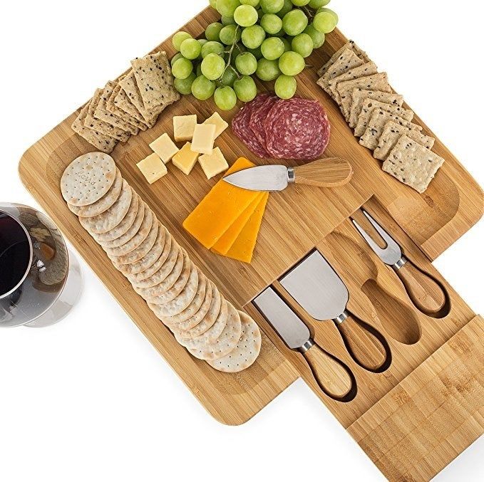 The wooden board features slots for crackers and a convenient sliding drawer for the knives.