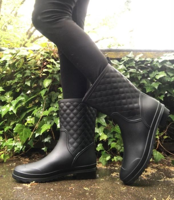 a photo of a reviewer wearing black leggings paired with the rainboots, taken outdoors