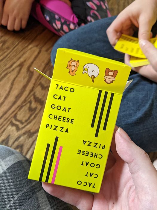 A photo of a reviewer holding the deck of Taco Cat Goat Cheese Pizza cards.