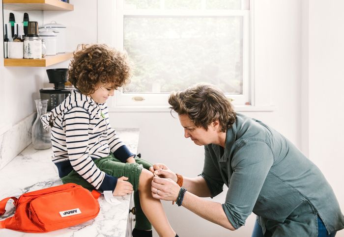 An adult applying a bandage to a child’s knee.
