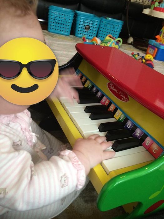 A photo of the reviewer’s toddler playing with the little wooden piano.