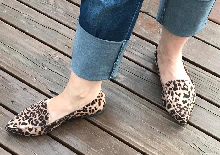 a reviewer dressed in jeans and animal-print pointed-toe loafers