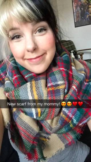A reviewer showcasing the scarf in a tan, blue, green, red, and yellow plaid pattern, captioned 