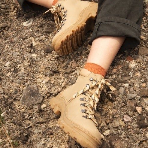 A person wearing stylish lace-up boots on rocky terrain