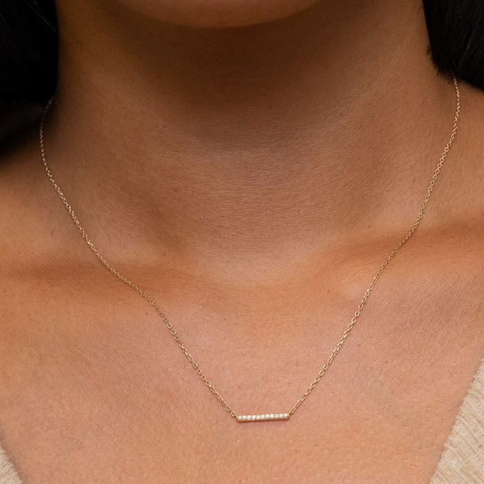 A model showcasing the yellow gold necklace adorned with tiny diamonds.