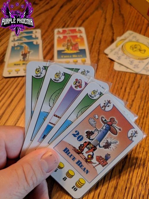 The reviewer is holding a handful of bean cards in the image.