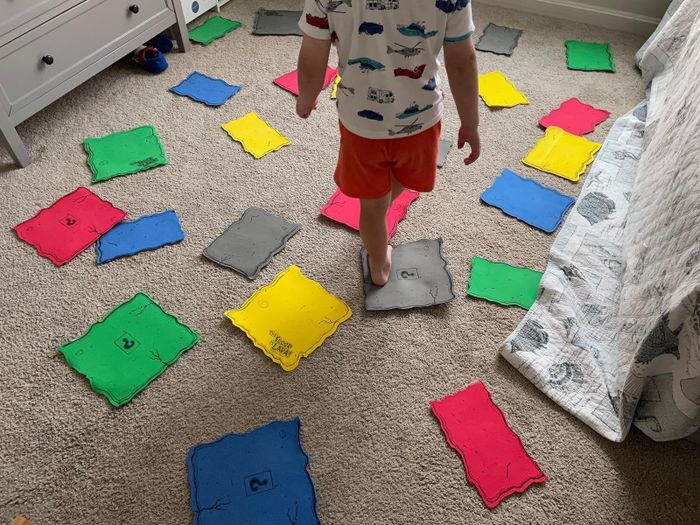 A photo of the reviewer’s child standing on a gray game tile, surrounded by colorful tiles on the floor.