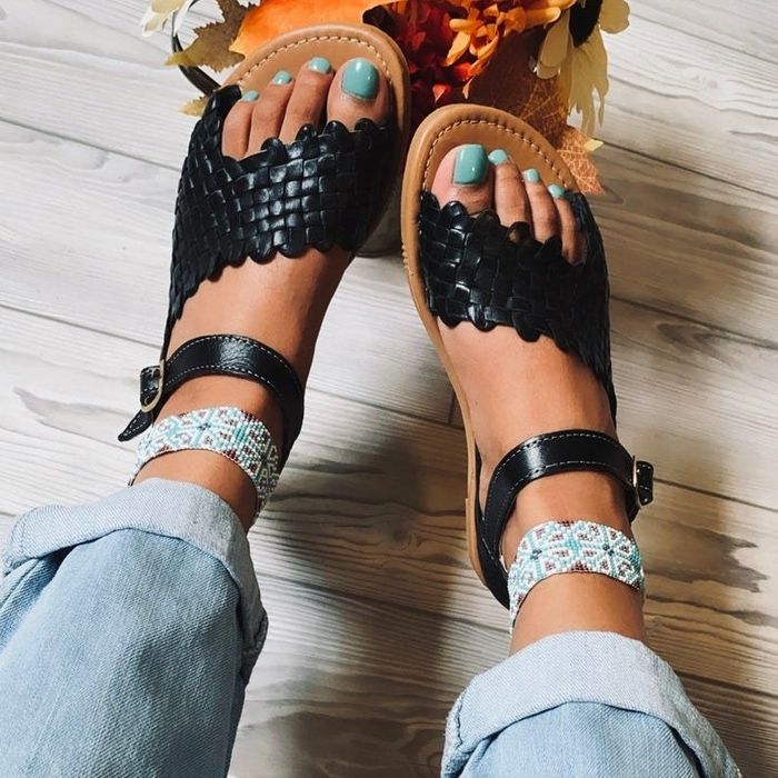 a model wearing the black version of the sandals
