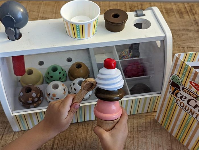 The reviewer posted an image of their child scooping pretend ice cream onto a fake cone.