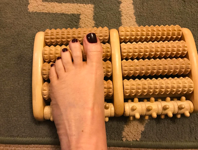 A reviewer’s foot placed on the four-roller device, one of which has a unique texture.