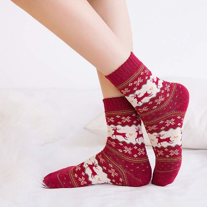 A model showcasing a red Fair Isle sweater paired with reindeer-themed socks.