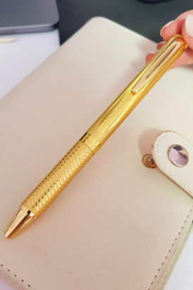 A reviewer holding the sleek, shiny gold pen.