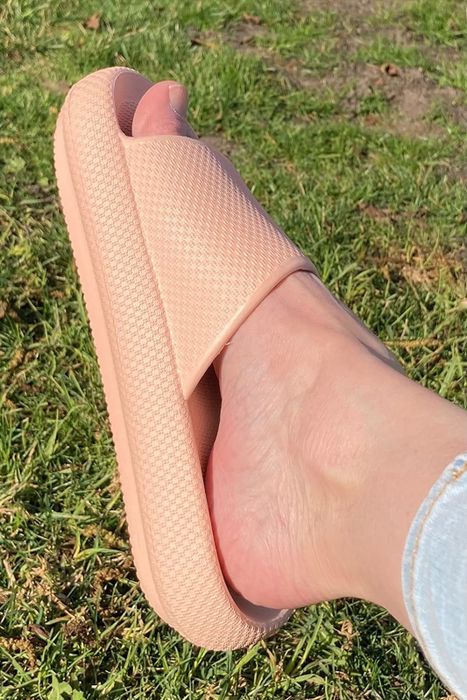 a side view of a reviewer wearing light pink slippers outdoors