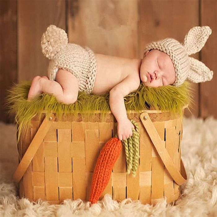 A staged baby photo featuring the little one in a basket, holding a carrot, and wearing the fluffy bunny tail bottoms and long-eared hat