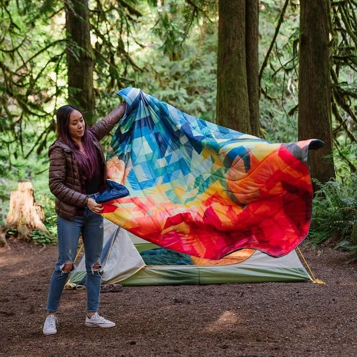 A girl setting up the blanket during a camping trip