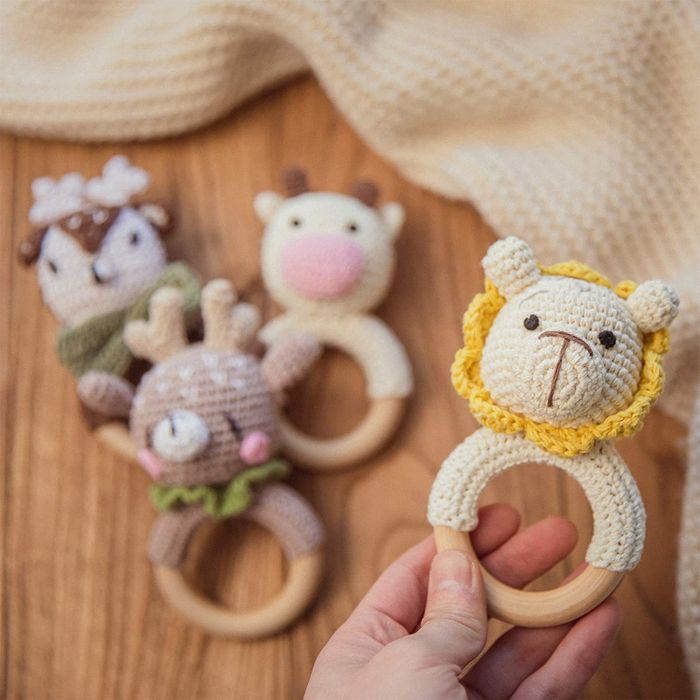 A person holding a knitted lion rattle, with several others blurred in the background