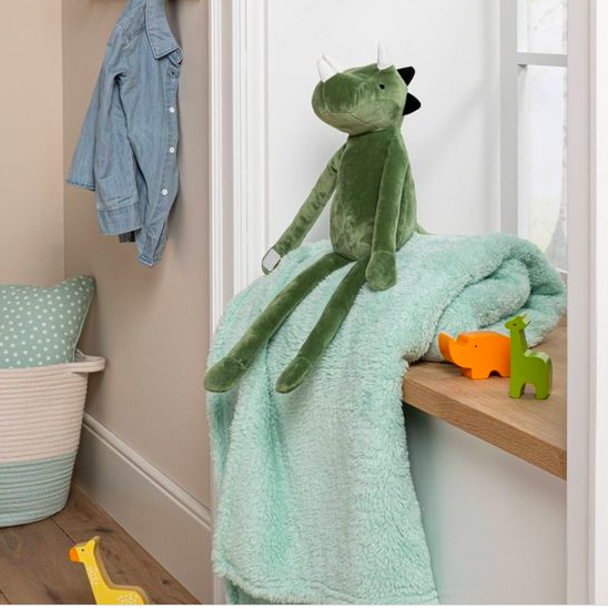a plush triceratops with long arms and legs resting on top of a mint green blanket in a nursery