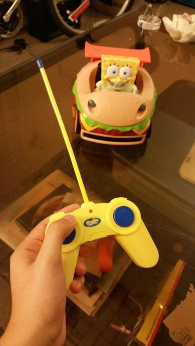 a reviewer holding a compact remote alongside a car that’s just slightly larger than their hand, placed on a table