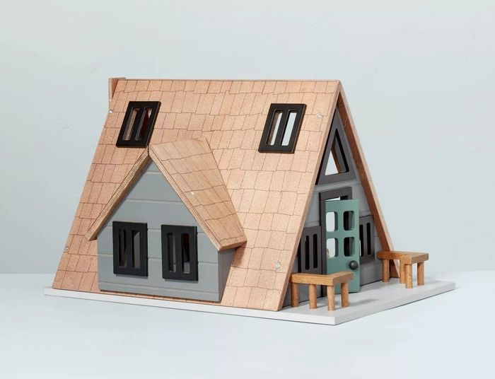 The exterior of a cabin-style toy showcasing the roof, front door, porch, and windows