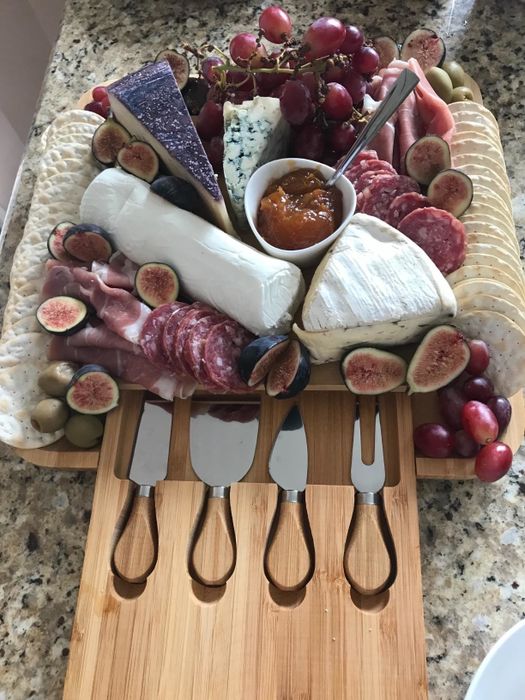 A reviewer’s board beautifully arranged with cheeses, grapes, crackers, and meats